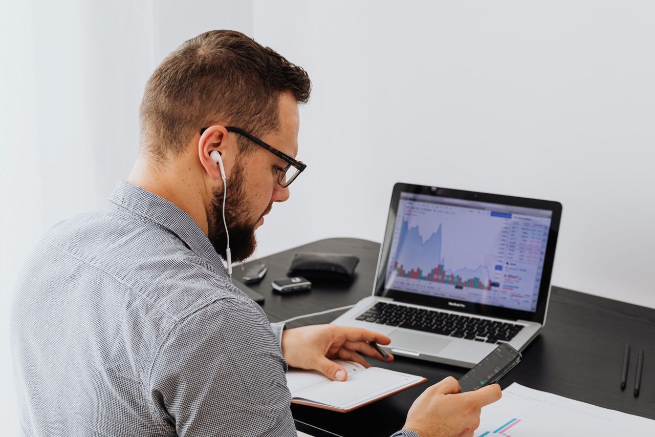 A man analysing graphs on his laptop in a bright office